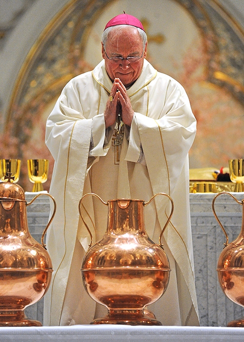 Bishop Richard Malone prays over a vessel of blessed olive oil at St. Joseph Cathedral during the annual Chrism Mass. (Dan Cappellazzo/Staff Photographer)